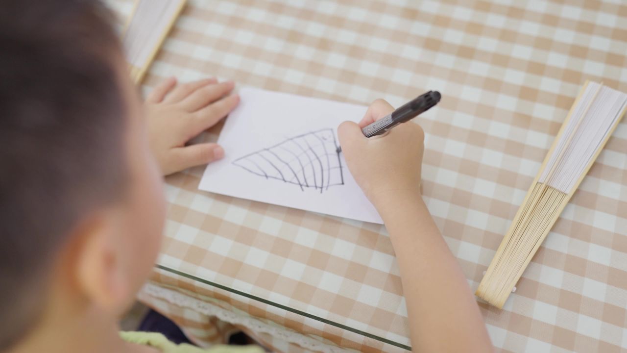 小男孩坐在桌前学画画
