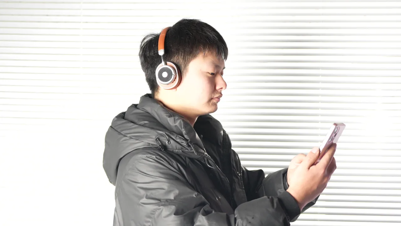 年轻男子戴耳机专注看手机侧面特写