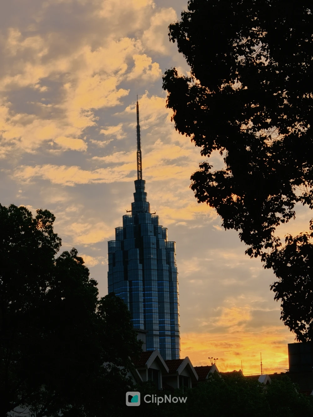 黄昏夕阳下现代摩天大楼剪影与金色云层城市风光