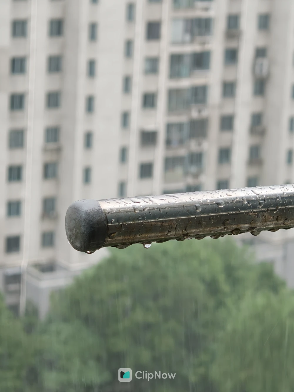 雨天窗边金属栏杆水珠特写与城市背景