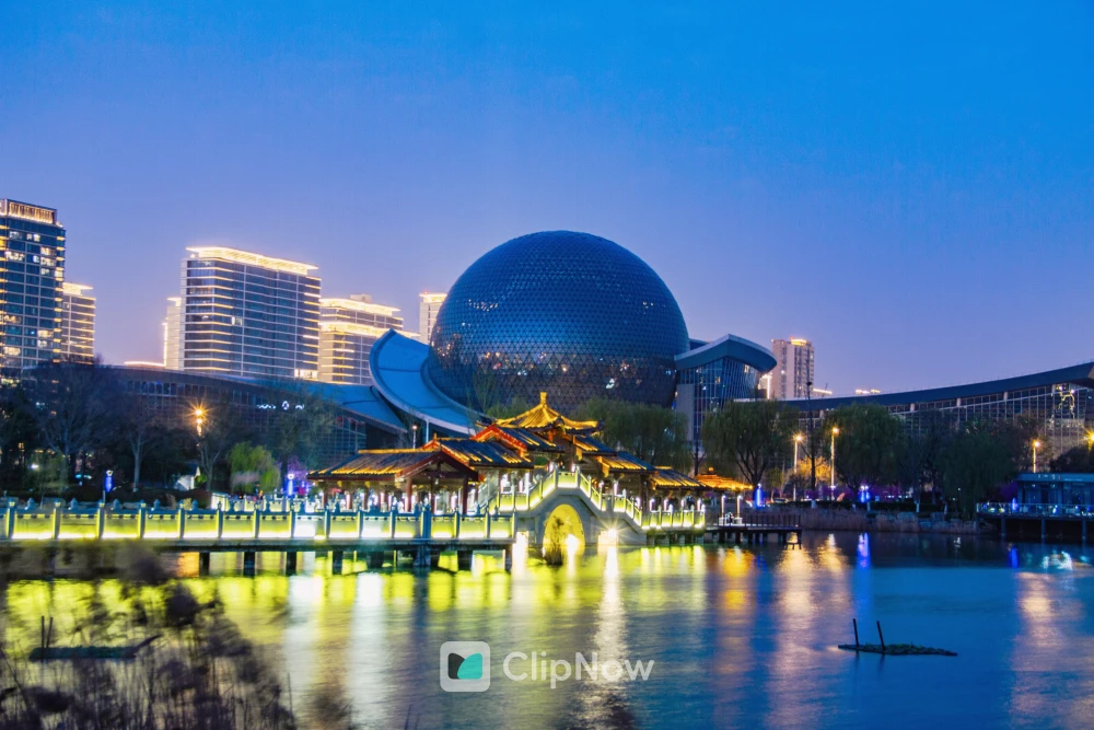 夜幕下蓝色球形建筑与中式亭台水景倒影城市风光