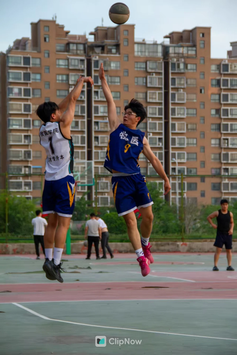 户外篮球场两名年轻男子激烈跳起争抢篮板球