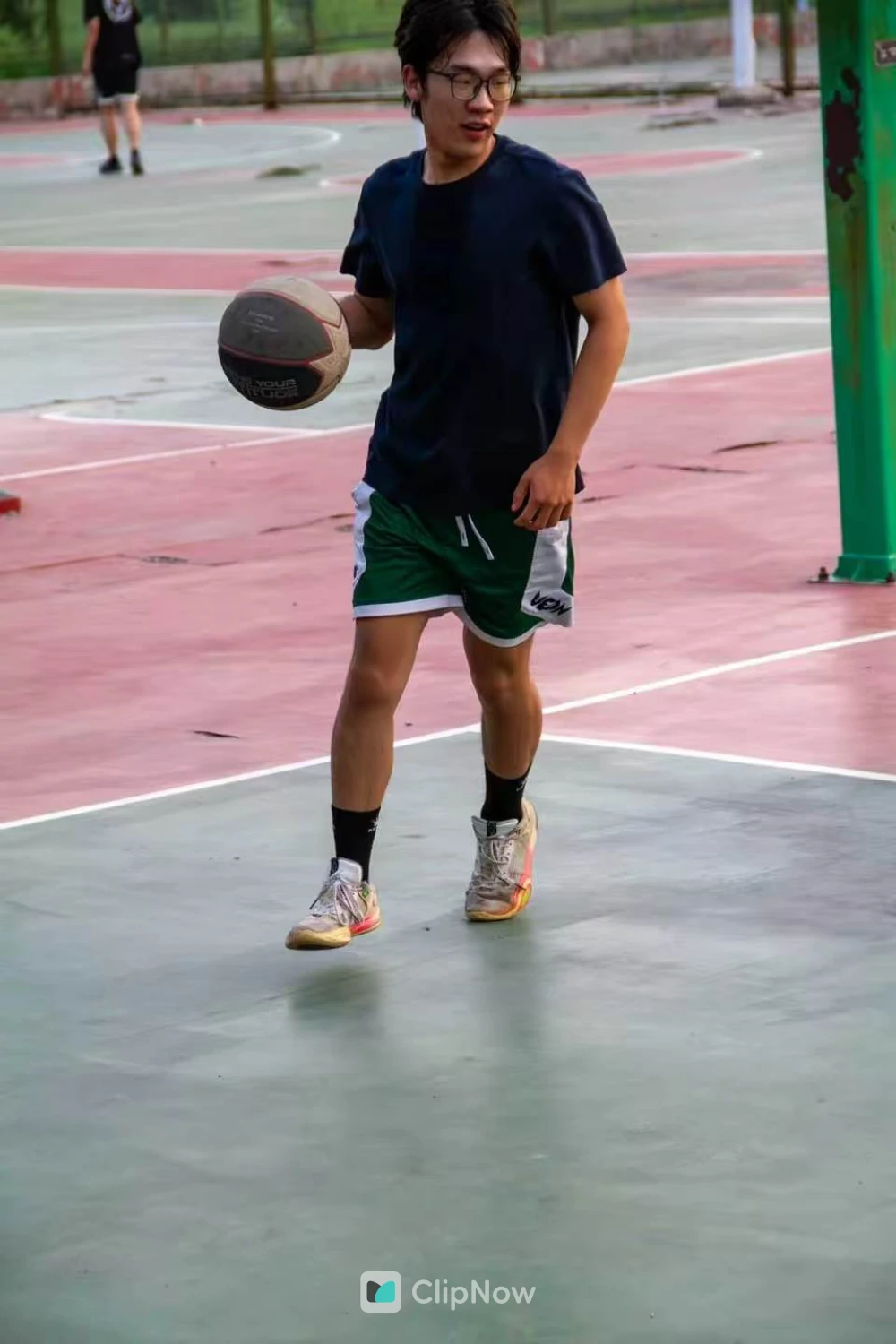 戴眼镜年轻男子户外篮球场运球特写