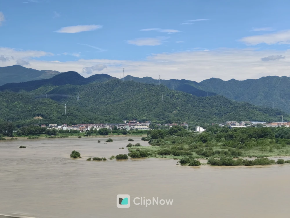 青山绿水间浑浊河流与远处村庄自然风光摄影