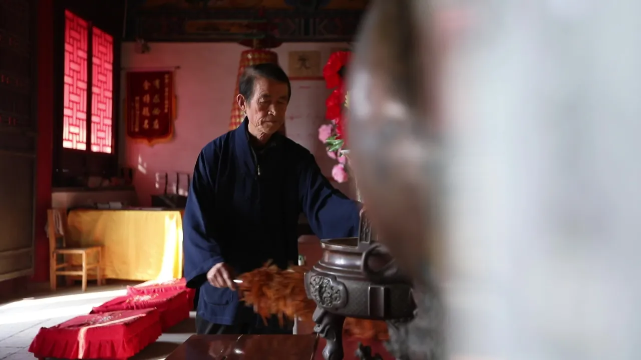 寺庙老者手持鸡毛掸子清扫香炉除尘