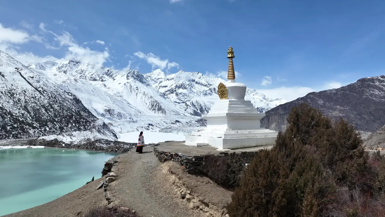 雪山湖泊旁白色佛塔与徒步者航拍