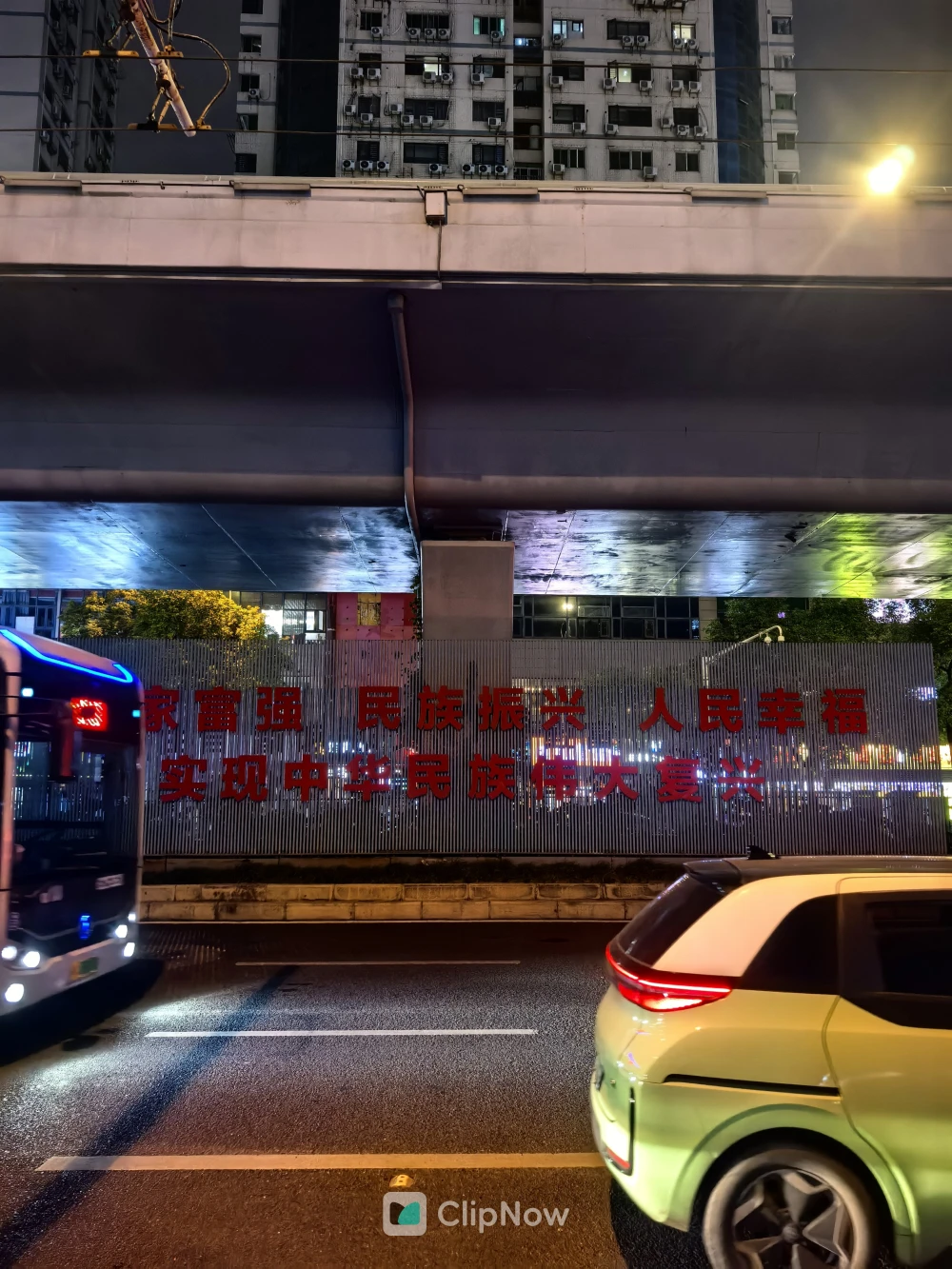 城市夜景立交桥下红色标语墙与行驶车辆