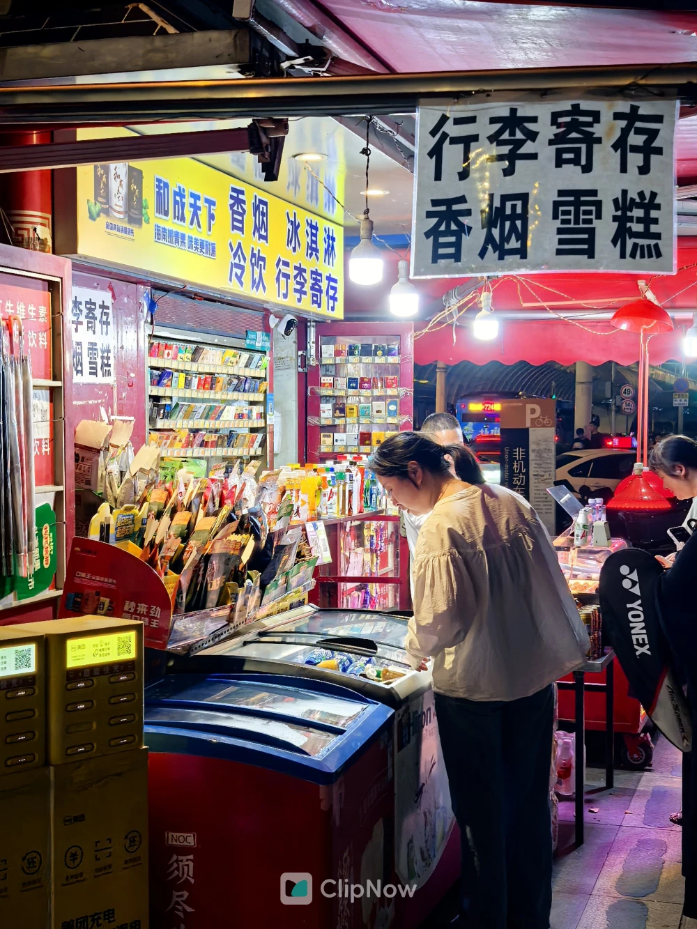 夜晚街头便利店顾客选购雪糕与行李寄存服务