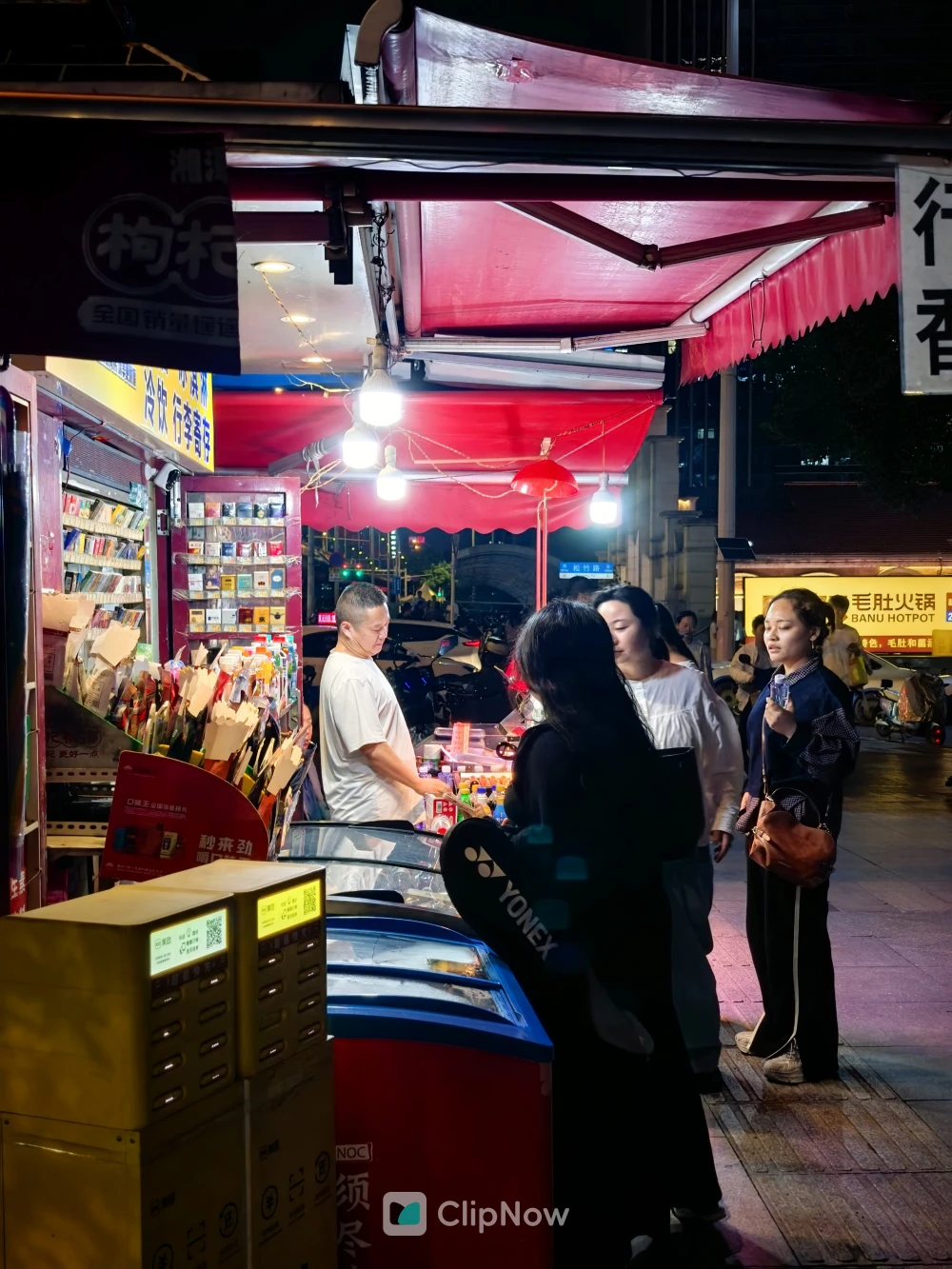 夜晚街头红色遮阳棚下便利店购物场景纪实摄影