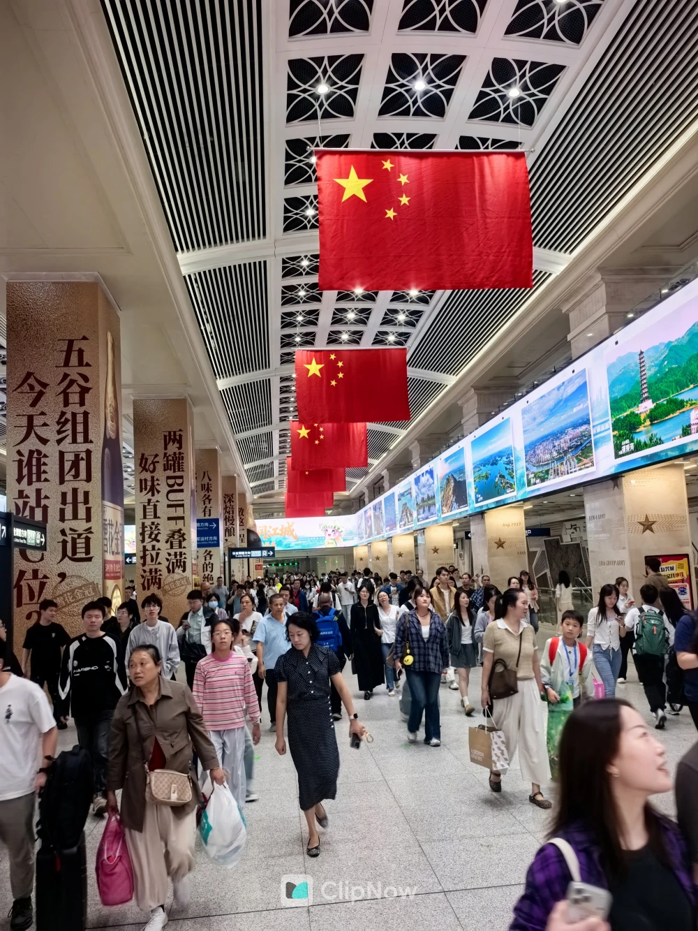 国庆氛围火车站大厅悬挂五星红旗与密集客流纪实摄影