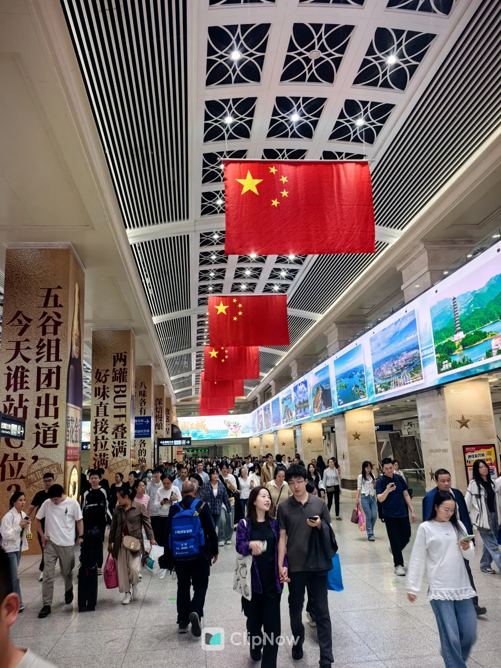 国庆期间繁忙的火车站大厅悬挂五星红旗人群熙攘