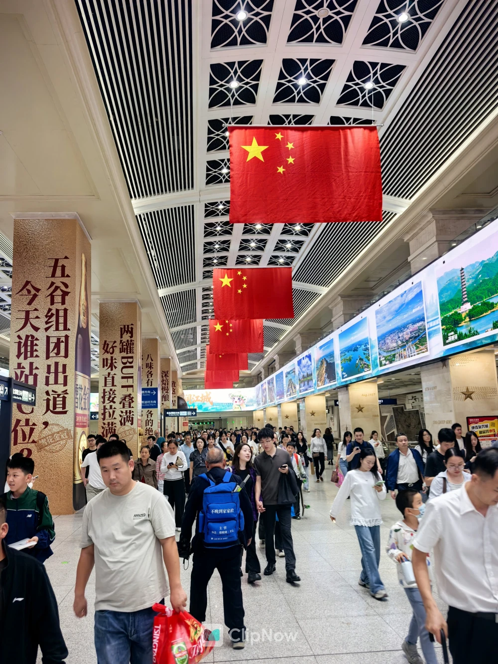 国庆期间中国火车站大厅悬挂五星红旗与熙攘人群摄影