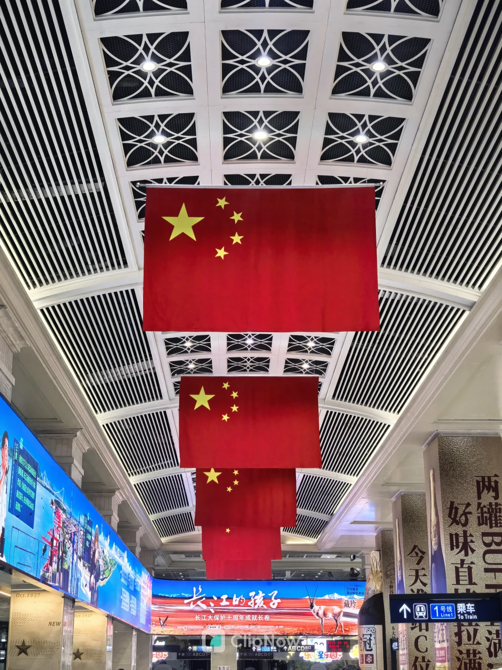 现代交通枢纽大厅内悬挂的五星红旗阵列仰拍